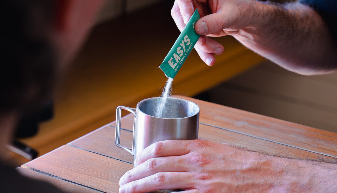A person pouring an Easys cocktail mix into a cup, showcasing how easy it is to make a delicious cocktail anywhere.