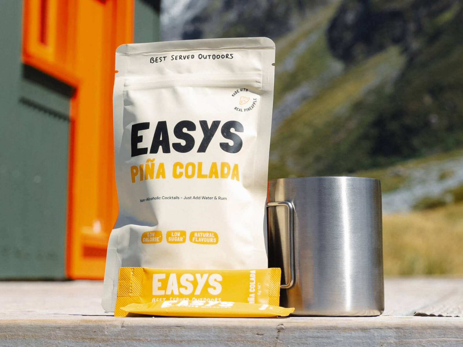 A refreshing Pina Colada made with Easys cocktail mix, placed outside a cozy backcountry hut, perfect for unwinding after a hike.
