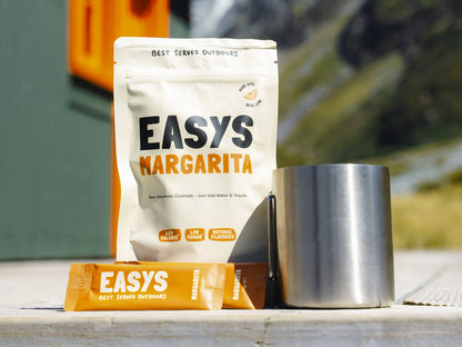 A refreshing Margarita made with Easys cocktail mix, placed outside a cozy backcountry hut, perfect for unwinding after a hike.